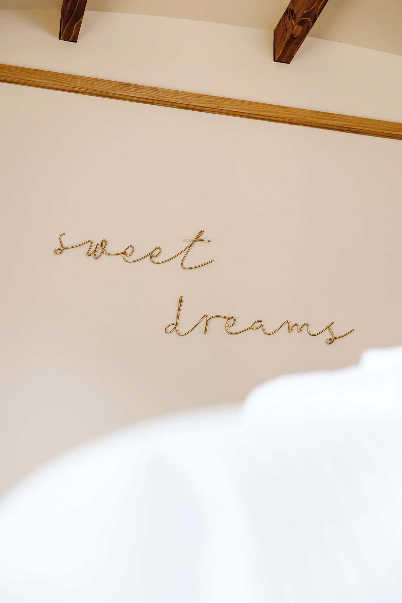 Una pared con la frase 'sweet dreams' escrita en letras doradas con caligrafía.