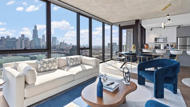 Un salon moderne doté d’une grande fenêtre, d’un canapé, d’une table basse et d’un coin repas avec des chaises et une table.