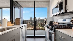 Une cuisine moderne avec vue sur la ville, des appareils en acier inoxydable et une grande fenêtre.