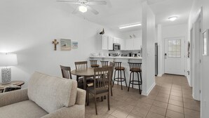 A modern kitchen with white cabinets, a microwave, and a coffee maker. There is a dining area with a table and chairs, and a ceiling fan above. - Seagrove 2BR near Lake & Beach + Free Tickets: Bikes, Dolphin Cruise & More! (Santa Rosa Beach)