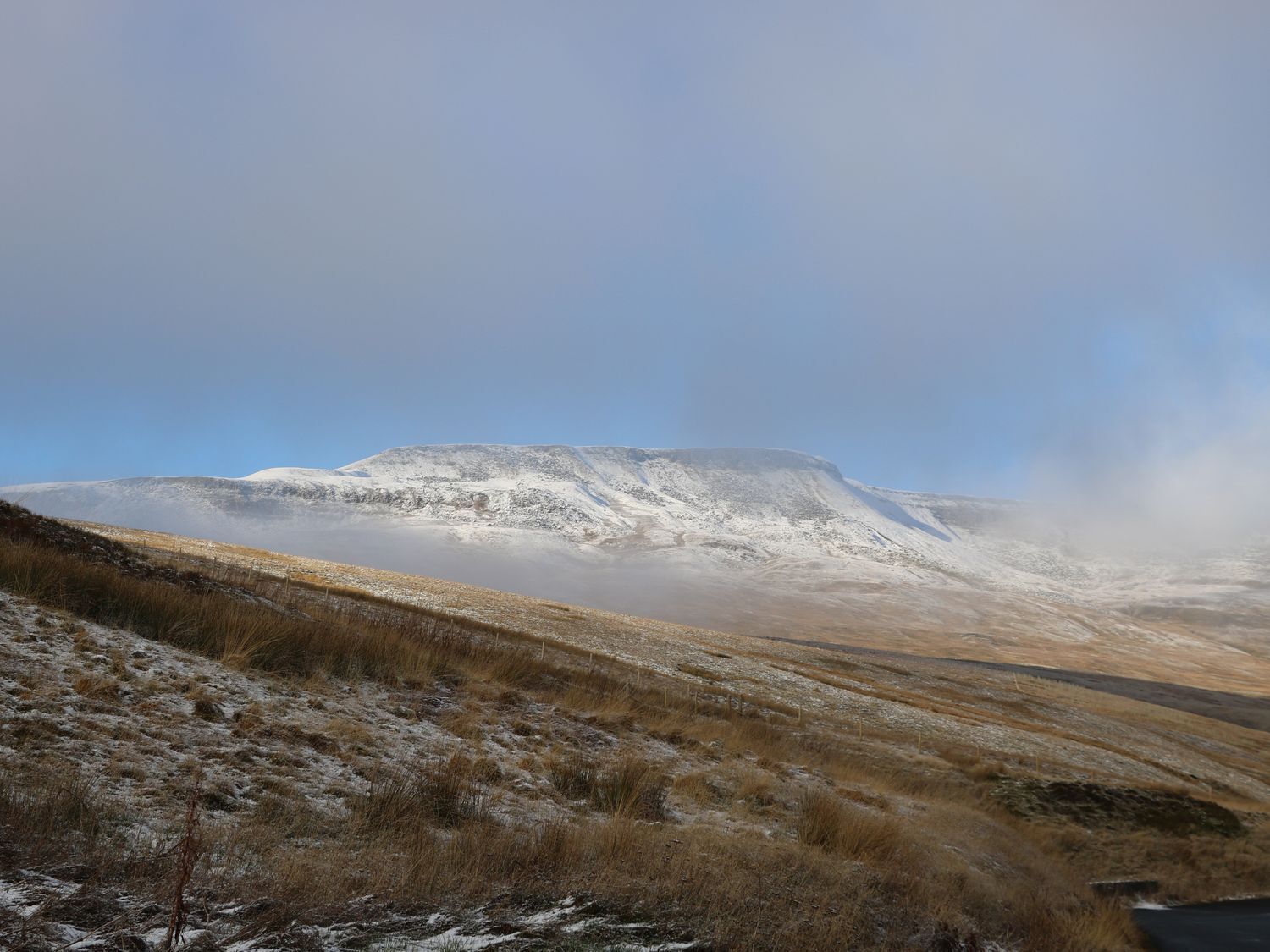 A mountainous landscape with a snow-covered peak and a clear sky.