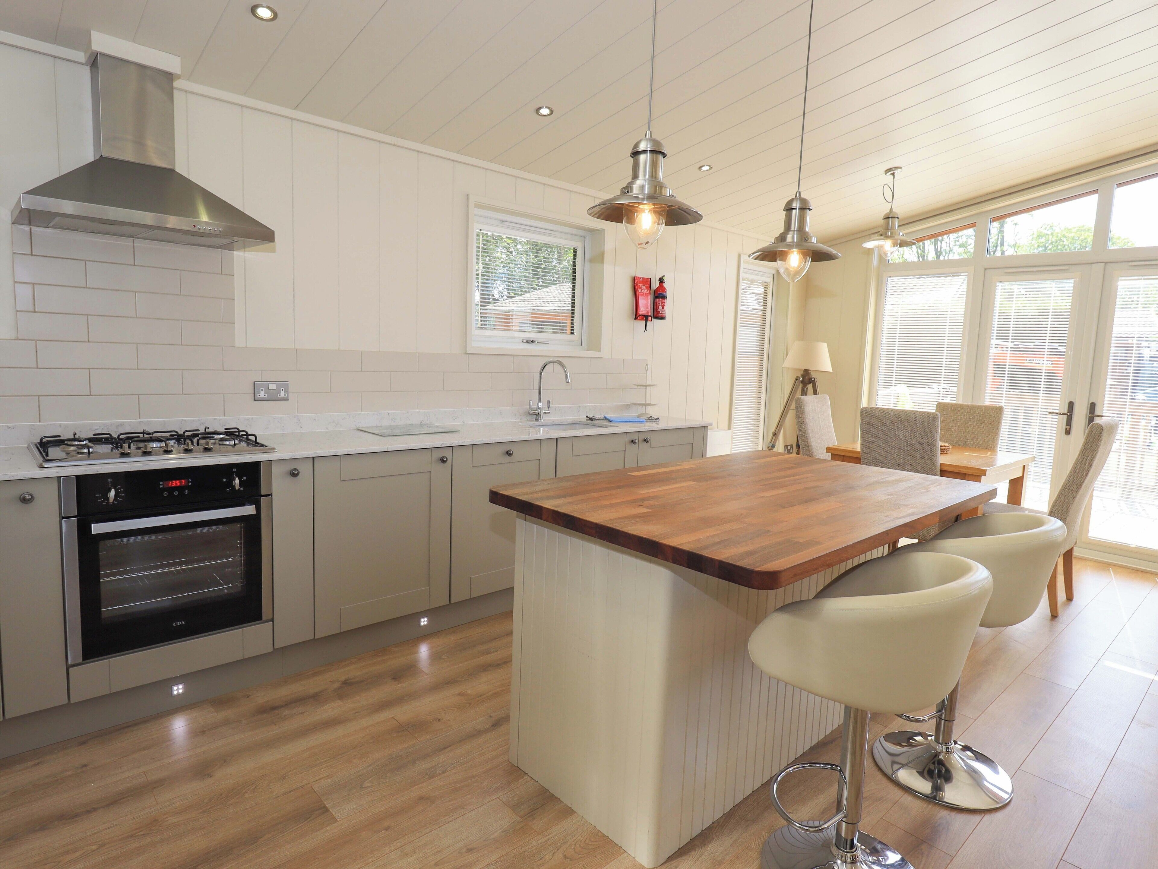 A modern kitchen with a central island, stainless steel appliances, and a large window providing natural light.