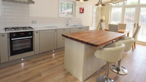 A modern kitchen with a central island, stainless steel appliances, and a large window providing natural light. - Kingfisher Lodge (Skipton)
