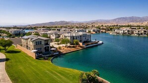 A residential area with houses by a lake, featuring a well-maintained lawn and clear blue water. - Solmar at Terra Lago Private Lake House With Free Pool Heating for any 3nights stay (Indio)