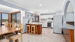 A modern kitchen with a central island, wooden chairs, and a dining table.