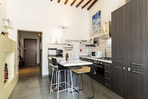 A modern kitchen with a central island, bar stools, and a view of the living area.
