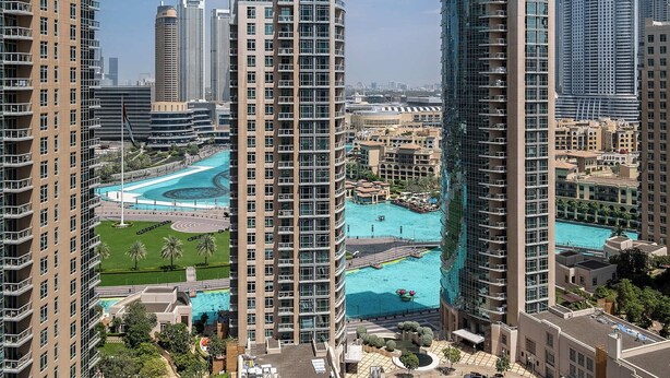 A high-rise building with a swimming pool surrounded by greenery and other buildings. - Bellavista - Elegant -2BR -Fountain View (Dubai)