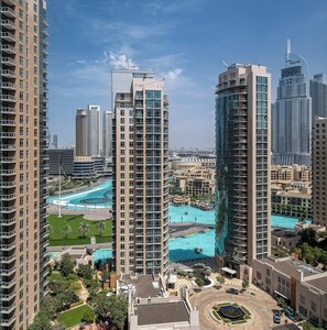 A high-rise building with a swimming pool surrounded by greenery and other buildings.
