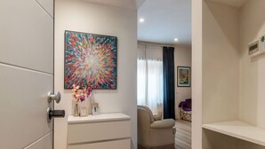 Un intérieur moderne avec un meuble blanc, un tableau abstrait aux couleurs vives, un canapé et un fauteuil.