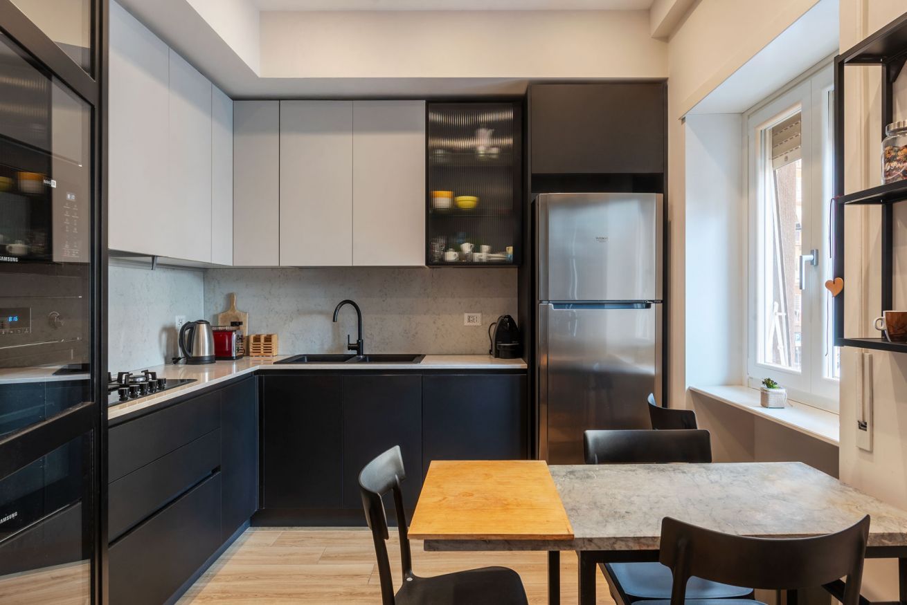 A compact kitchen with modern appliances, a dining area with a marble table, and a window providing natural light.