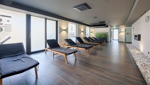 A modern spa with wooden flooring, black lounge chairs, and large windows. - Apartamenty Sun & Snow Koło Brzegu SPA (Kolobrzeg)