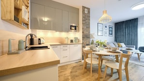 A modern kitchen with a wooden countertop, built-in appliances, and a dining area with a round table and chairs. - Apartamenty Sun & Snow Koło Brzegu SPA (Kolobrzeg)