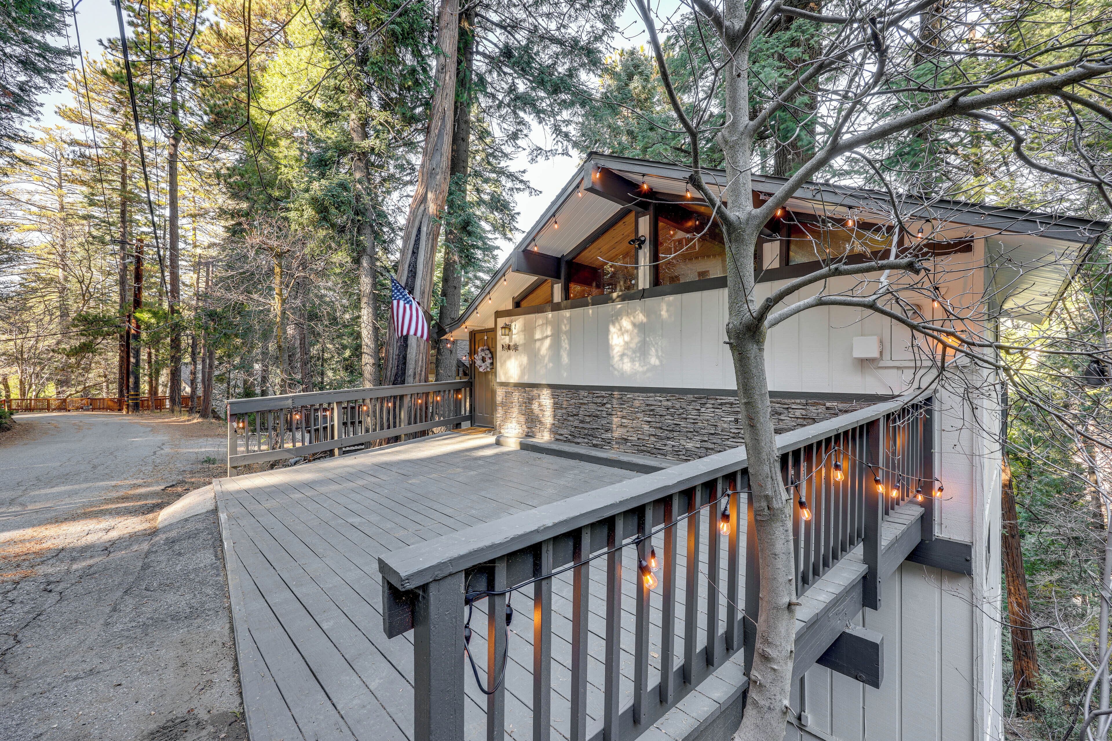 A cabin with a deck, surrounded by tall trees.
