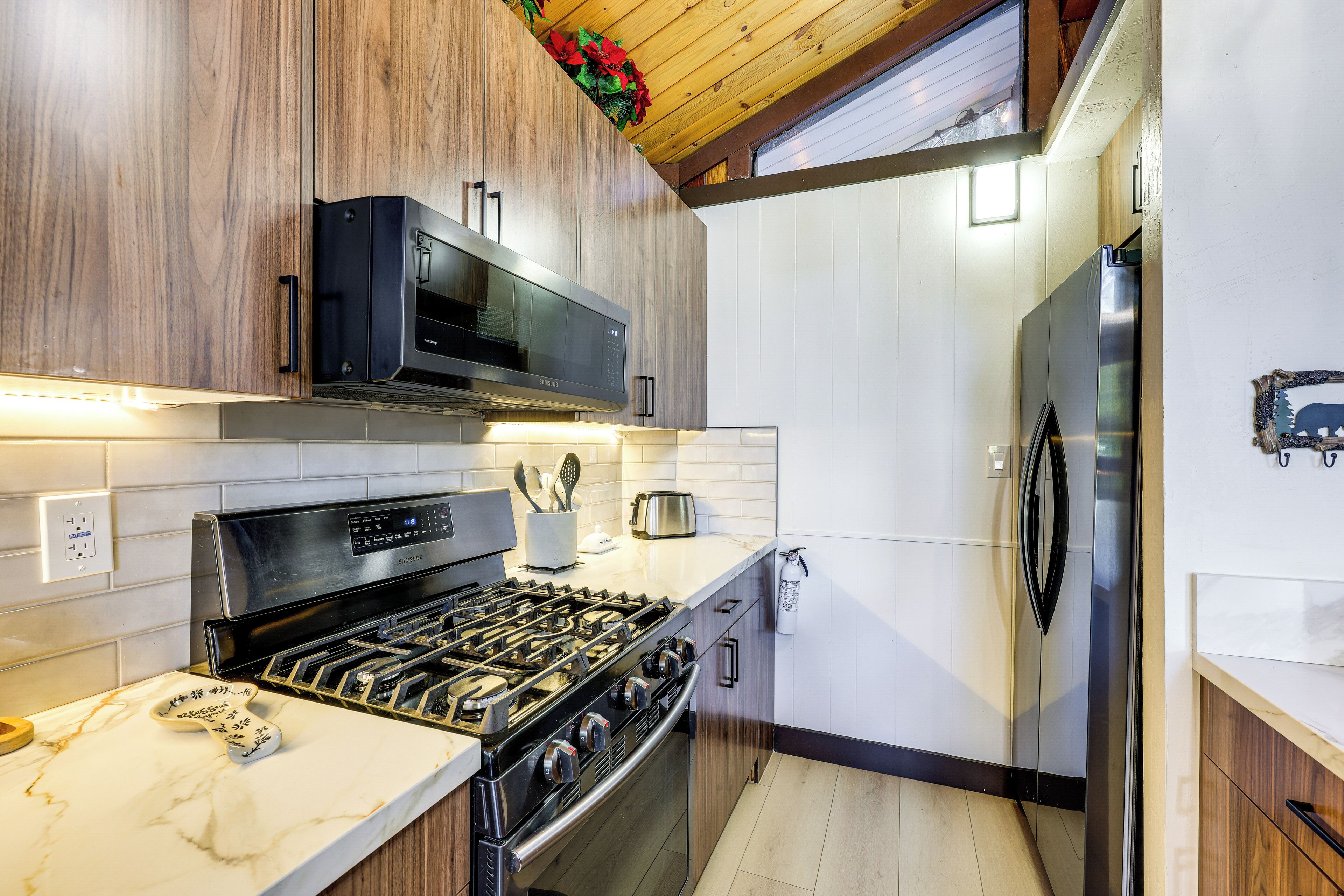 Una cocina moderna con estufa a gas, microondas y refrigerador de acero inoxidable.