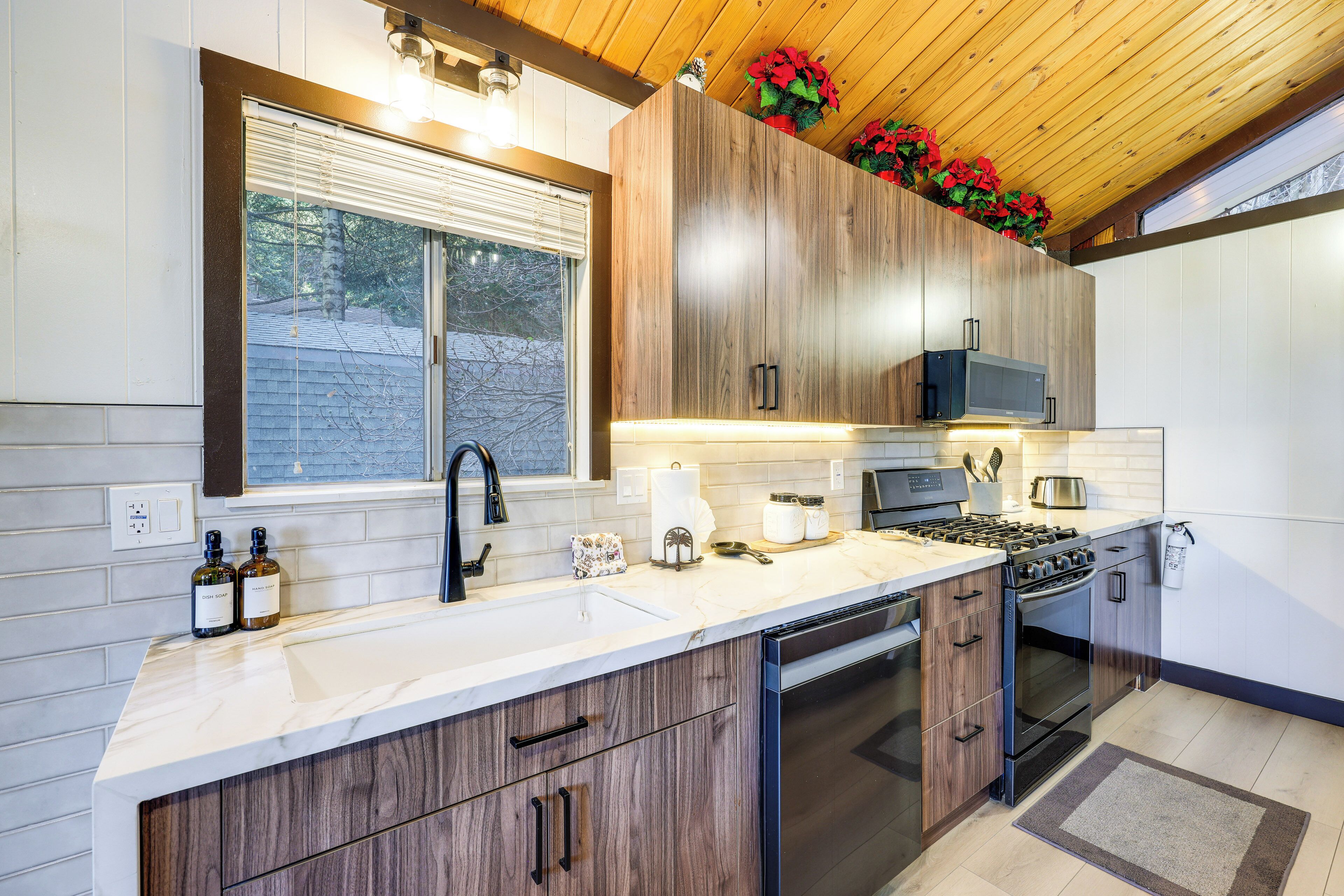 Una cocina moderna con armarios de madera, un lavamanos de acero inoxidable y un microondas integrado.