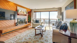 A spacious living room with a large flat-screen TV, a sofa, a coffee table, and a balcony with a view. - Pool Access: Scenic Condo in Wintergreen Resort! (Nellysford)