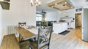 Eine moderne Küche mit weißen Schränken, einer zentralen Kochinsel und einem Essbereich mit Holztisch und Stühlen.