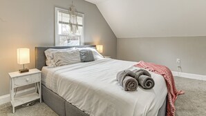 A bedroom with a bed, nightstand, lamp, and a window with blinds. - 4 Mi to Universities: Quaint Parkville Apartment! (Parkville)