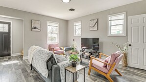 A living room with a grey sofa, a pink armchair, a coffee table, and a TV. - 4 Mi to Universities: Quaint Parkville Apartment! (Parkville)