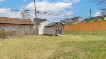 A backyard with a wooden shed, a wooden fence, and houses in the background.