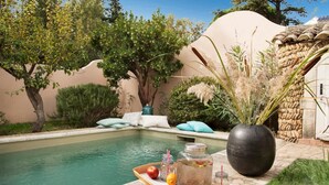 A poolside area with a tray of fruits and a large vase. - Proven ale House With Pool and spa (Noves)