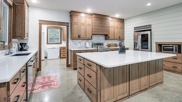 A modern kitchen with wooden cabinets, a large island, and built-in appliances. - Great for Groups: Family Creekside Home in Loretto (Loretto)