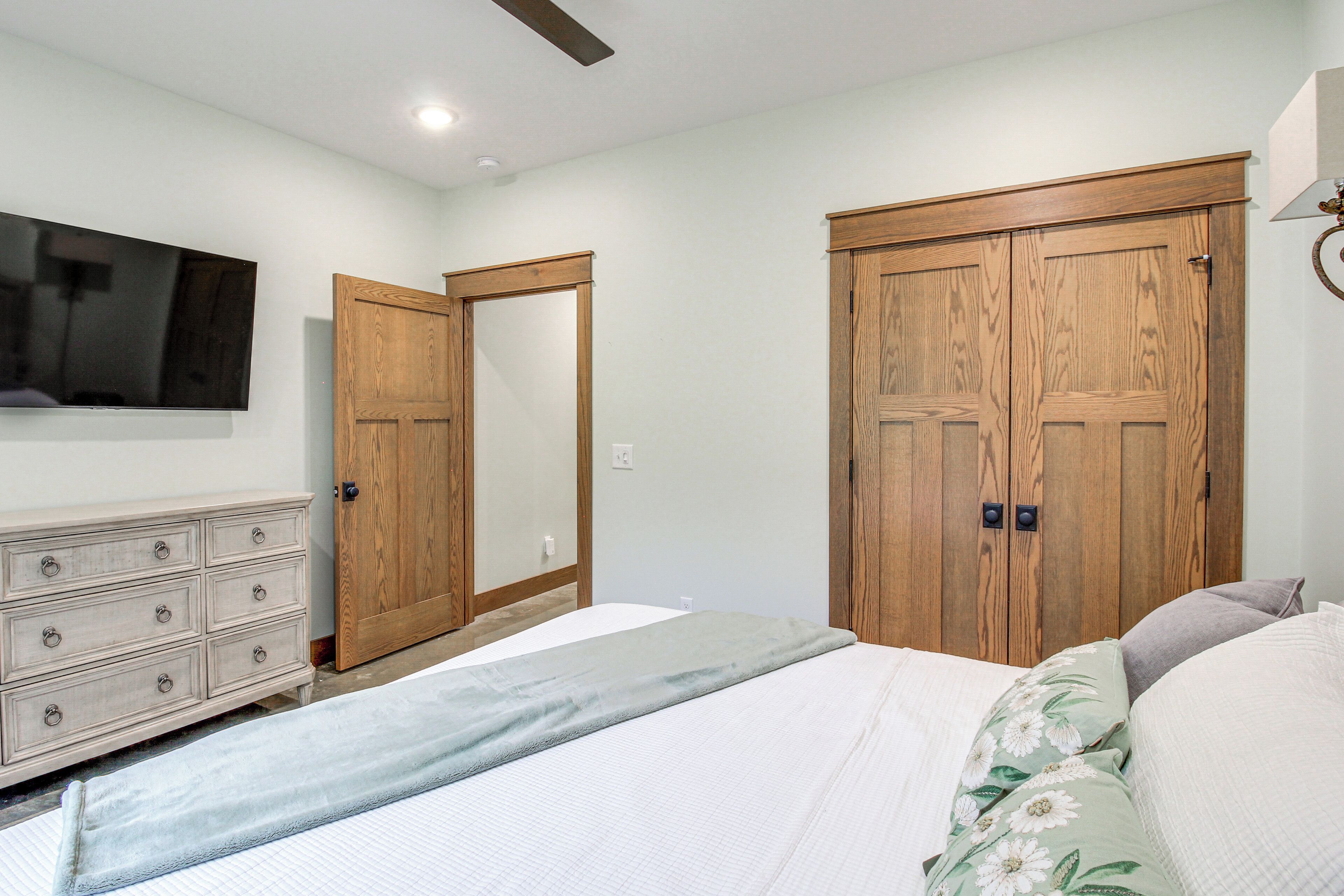 Une chambre à coucher comprenant un lit, une commode, un téléviseur et deux armoires en bois.