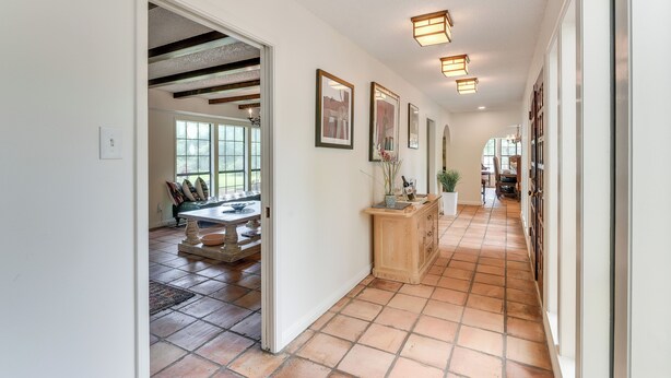 A hallway with tiled flooring, wooden cabinets, and framed pictures on the walls. - 2 Mi to Dtwn: Spacious Angleton Home w/ Courtyard! (Angleton)