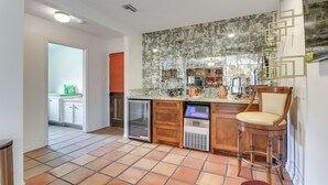 A kitchen with a tiled backsplash, a refrigerator, a sink, and a bar stool. - 2 Mi to Dtwn: Spacious Angleton Home w/ Courtyard! (Angleton)