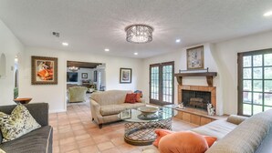 A spacious living room with a fireplace, comfortable seating, and a dining area in the background. - 2 Mi to Dtwn: Spacious Angleton Home w/ Courtyard! (Angleton)