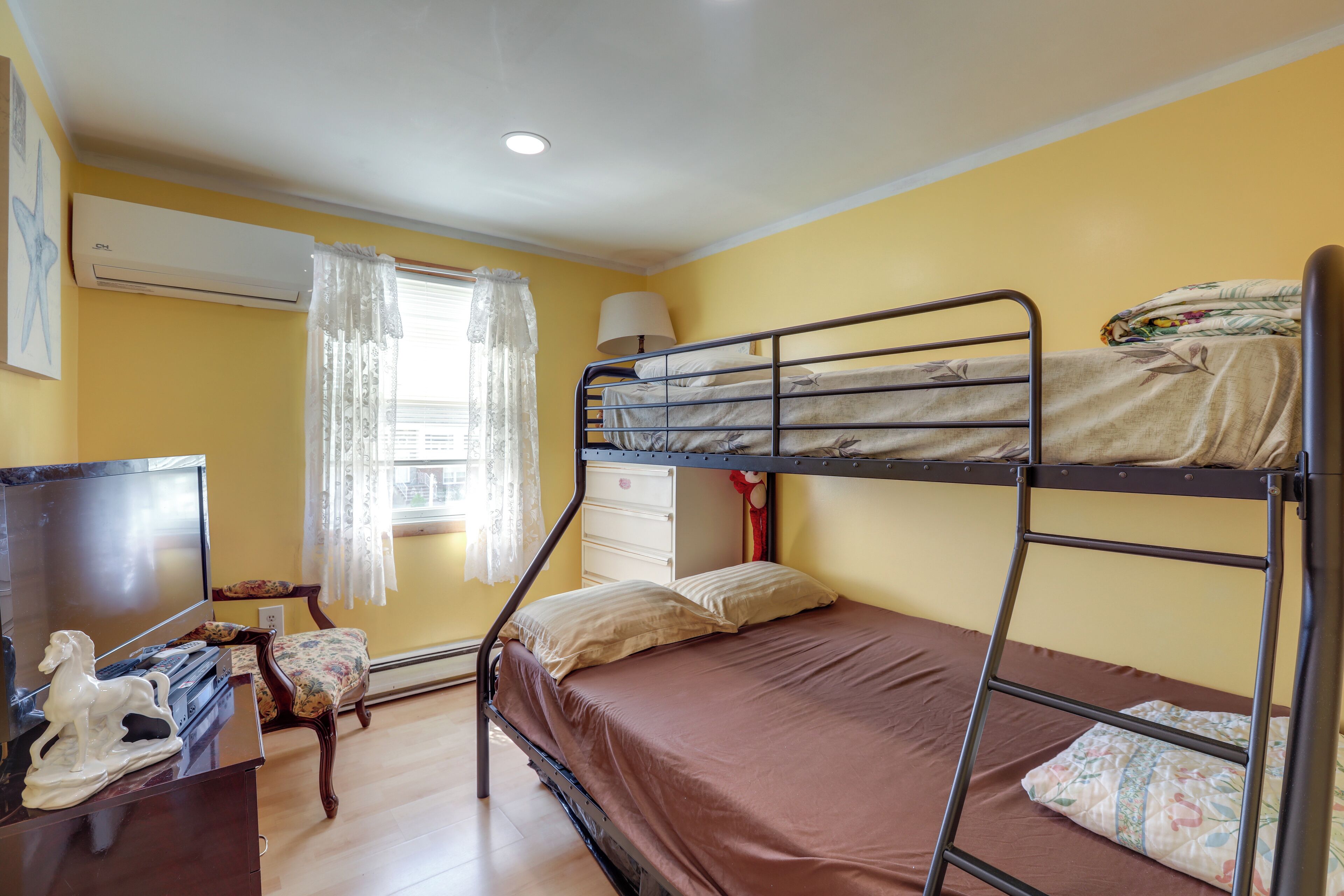 Une chambre avec un lit superposé, un bureau, une chaise et un téléviseur.