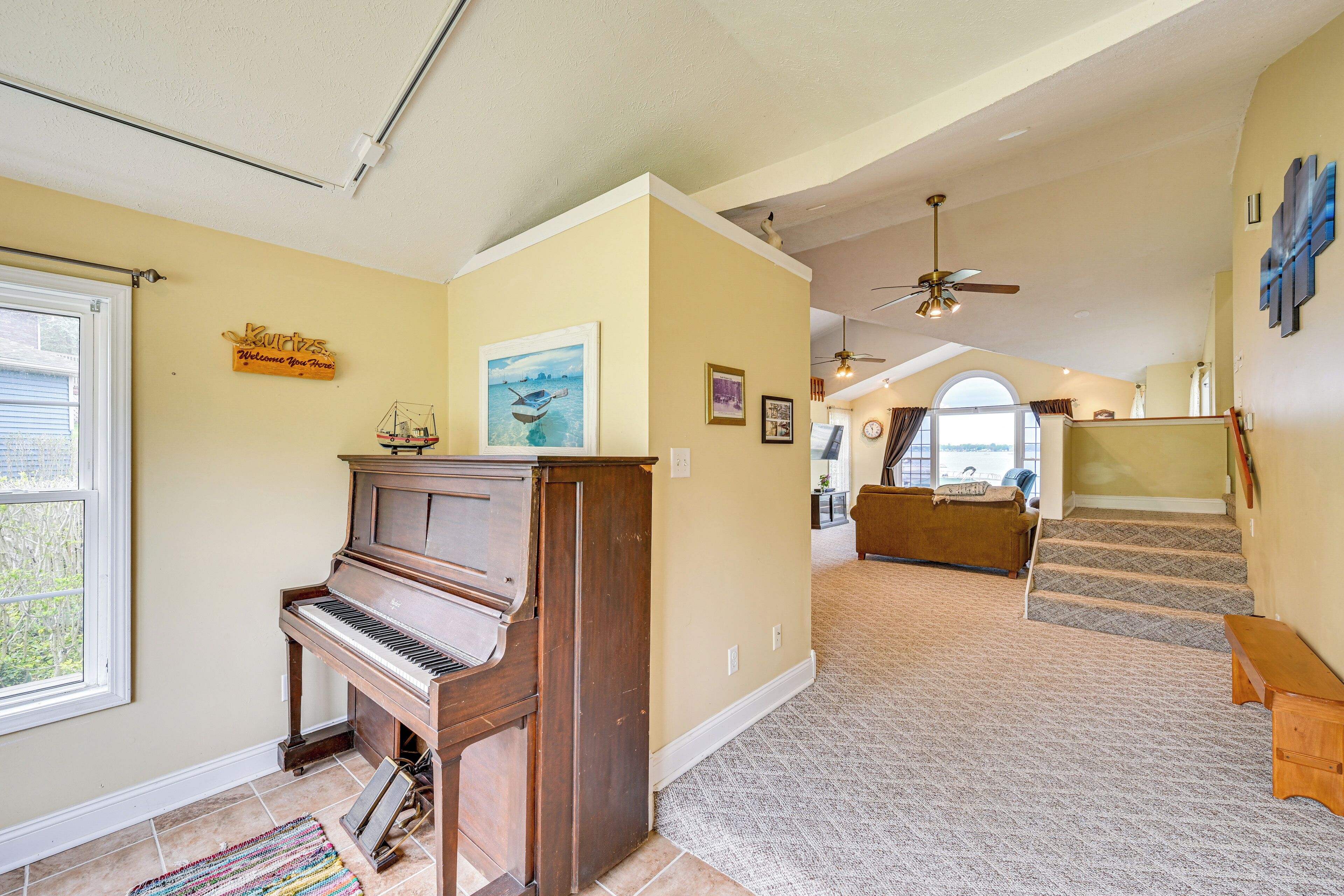 Amplia sala de estar con un piano, una escalera y vistas al exterior.
