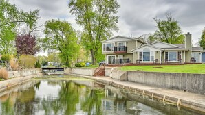 A two-story house with a front yard, a small pond, and a bridge leading to a garage. - Scenic Views: Spacious Webster Lake House! (North Webster)