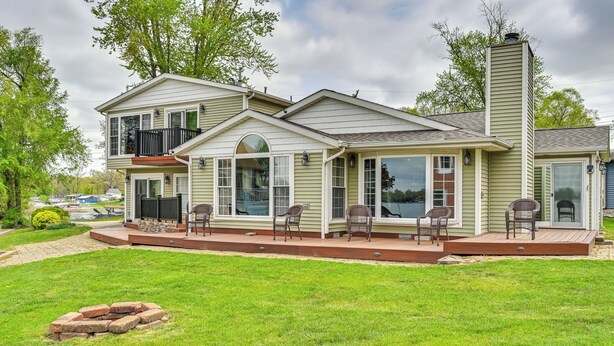 A two-story house with a covered patio area, large windows, and a chimney. - Scenic Views: Spacious Webster Lake House! (North Webster)
