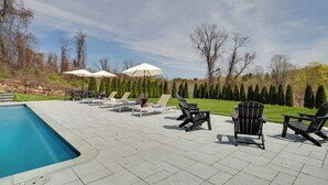 A poolside area with lounge chairs, umbrellas, and a clear view of the surrounding landscape. - Outdoor Entertainment Areas: Spacious Katonah Gem! (Katonah)