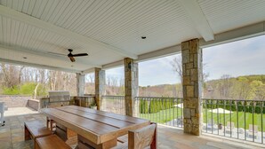 An outdoor patio with a wooden table and benches, stone pillars, and a view of a well-maintained lawn and trees. - Outdoor Entertainment Areas: Spacious Katonah Gem! (Katonah)