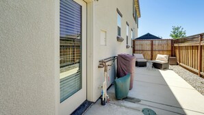 A patio with outdoor furniture, a covered grill, and a wooden fence.