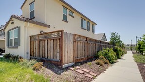 A two-story house with a wooden fence, a paved driveway, and a sidewalk.