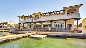 A two-story building with a balcony, a 'For Sale' sign, and a pool area with a dock. - Game Room + Dock: Riverfront Escape in Parker! (Parker)