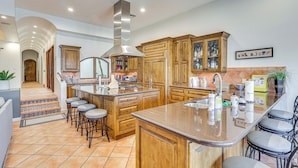 A spacious kitchen with wooden cabinets, a large island with bar stools, and a stainless steel range hood. - Game Room + Dock: Riverfront Escape in Parker! (Parker)