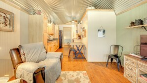 A cozy living room with a leather sofa, a dining table with chairs, a wooden cabinet, and a television on a dresser. - Cozy Couple's Cabin Retreat in Concan! (Concan)