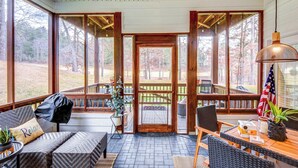 A covered porch with outdoor seating, large windows, and an American flag. - Modern Condo + Golf Course View, Near Hiking! (Clayton)