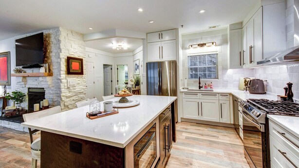 A modern kitchen with a large island, built-in appliances, and a stone accent wall. - Modern Condo + Golf Course View, Near Hiking! (Clayton)