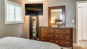 Un dormitorio con cama, cómoda, televisor y espejo.