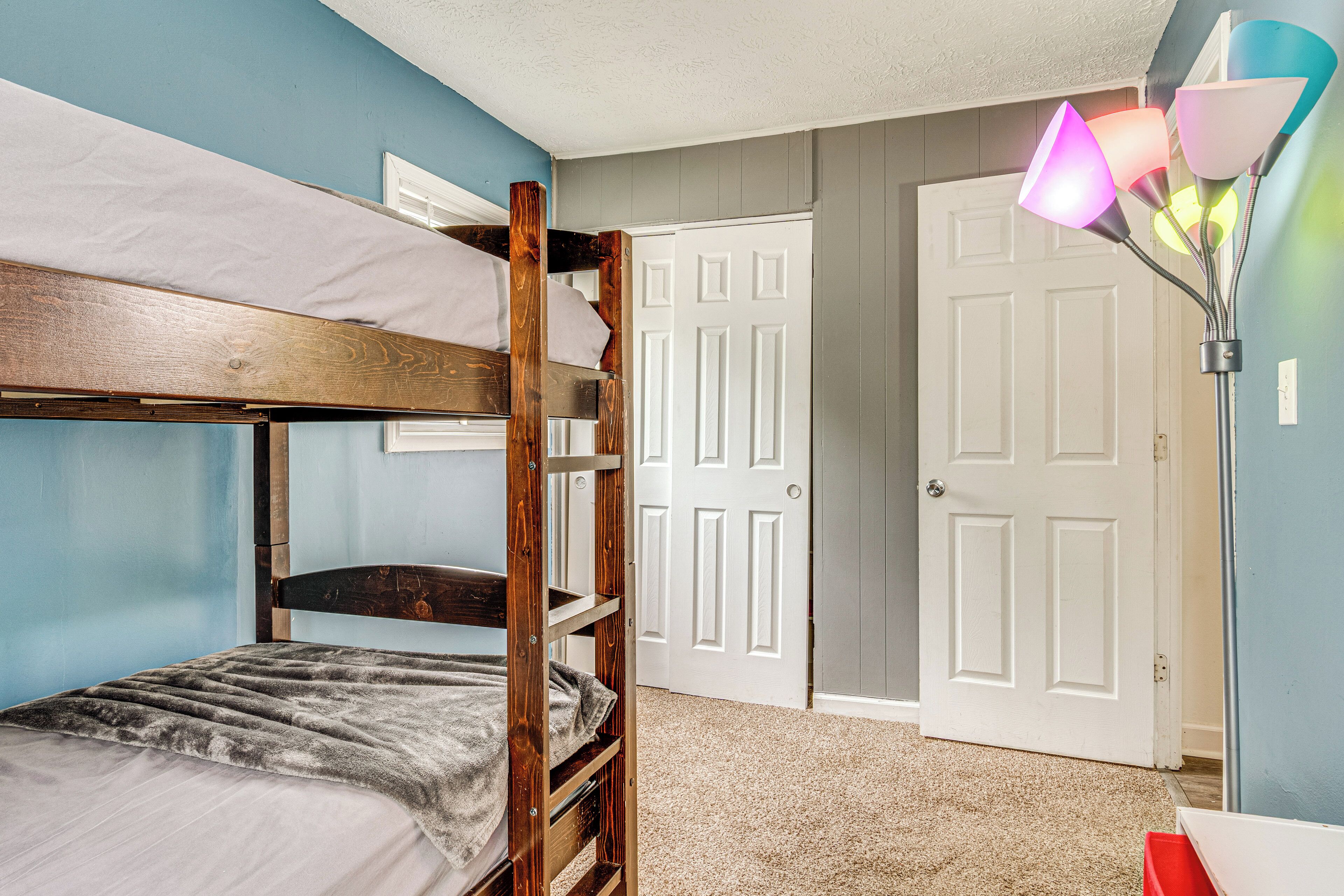 A bunk bed room with a door and a lamp.