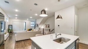 A modern kitchen with a central island, stainless steel sink, and pendant lighting. - 10 Mi to Dtwn Dallas: Sleek Retreat w/ Balcony (Dallas)