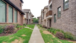 A residential building with brick facades, a central concrete pathway, and small front yards with shrubs. - 10 Mi to Dtwn Dallas: Sleek Retreat w/ Balcony (Dallas)