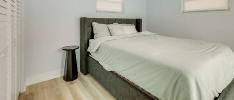 Ein Schlafzimmer mit einem Bett, einem Deckenventilator und zwei Fenstern mit Jalousien.
