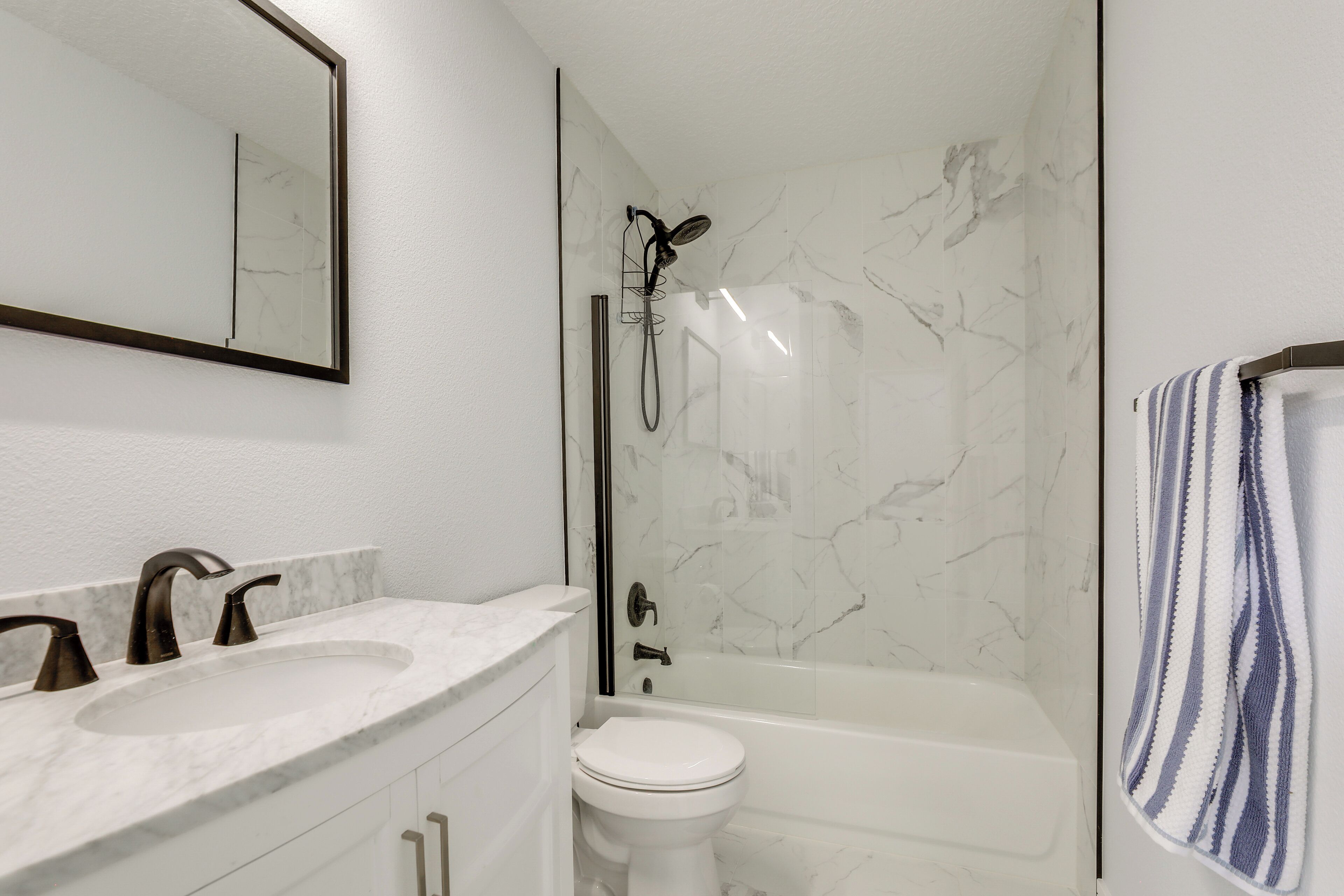 A bathroom with a white marble sink, a toilet, and a bathtub.