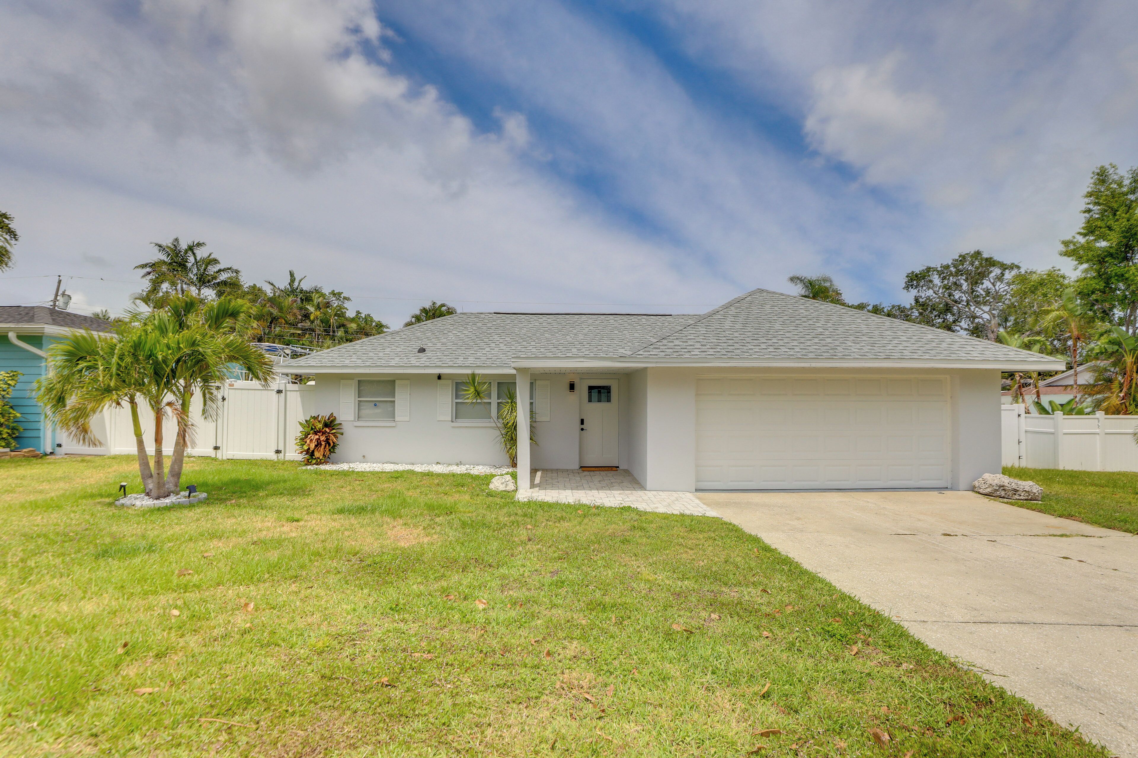 A single-story house with a garage, a front lawn, and a palm tree.